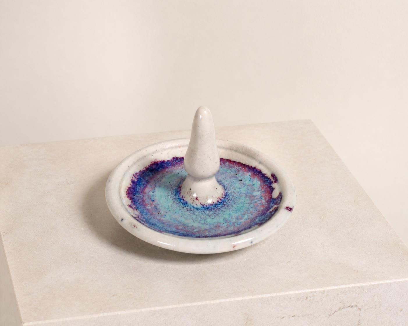 A white ceramic ring dish with blue and purple glaze